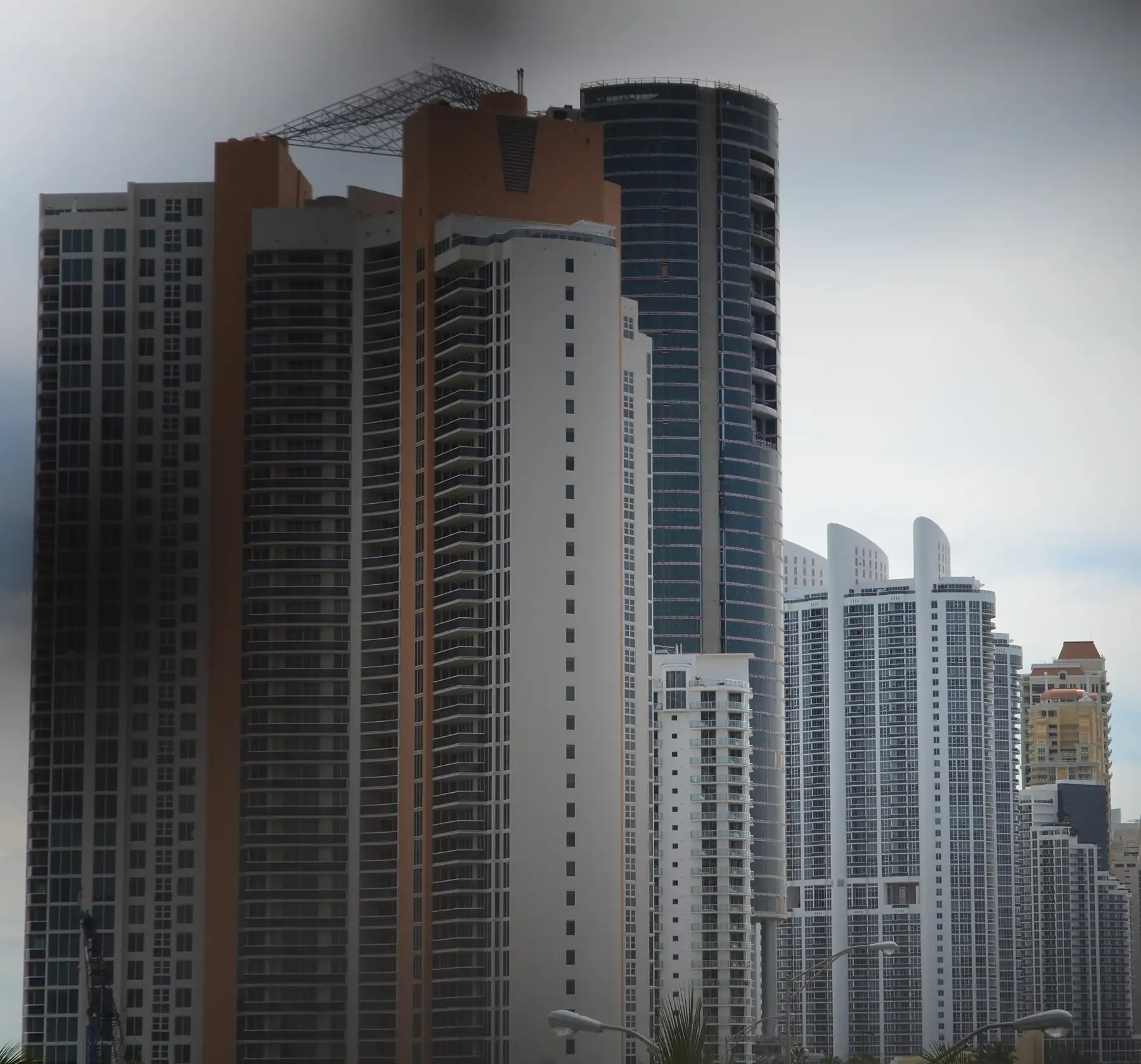 The dark round tower of Porsche Design Tower near completion, February 2016, among its Sunny Isles neighbors — Porsche Design Tower, Sunny Isles Beach