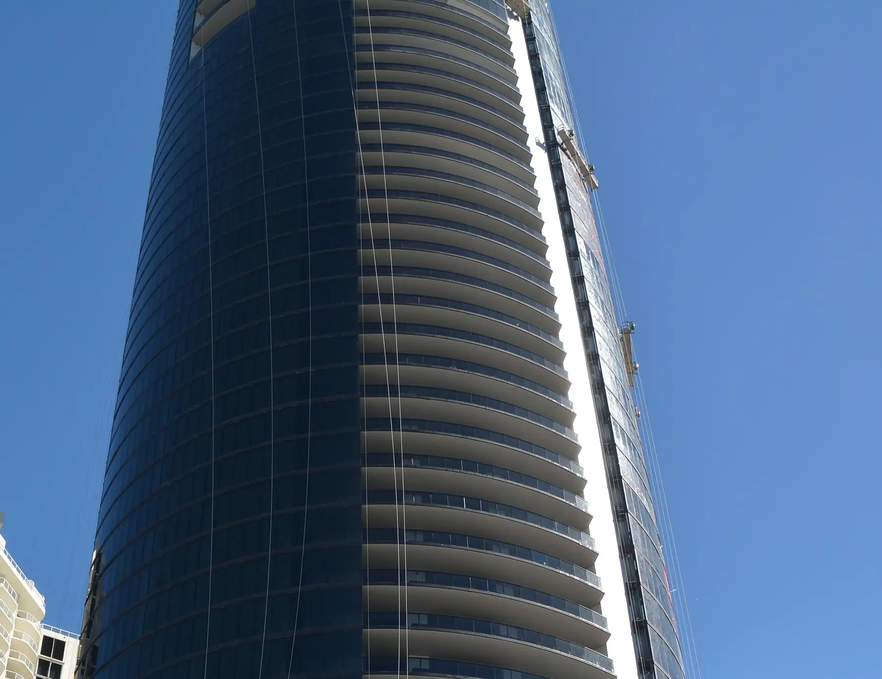 Porsche Design Tower, a dark glass cylinder, seen from Collins Avenue near completion in 2016